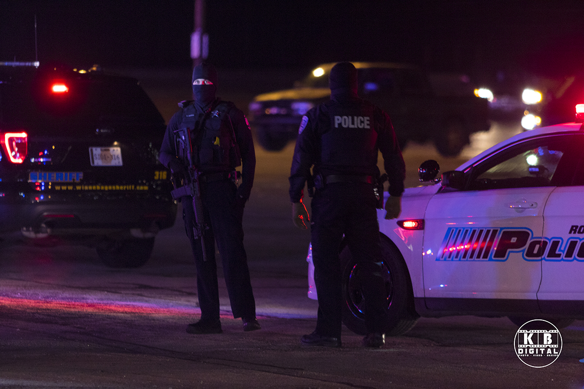 Heavily armed policemen outside of the building.